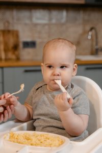 niemowlę jedzące posiłek w krzesełku do karmienia