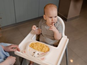 dziecko jedzące w krzesełku do karmienia