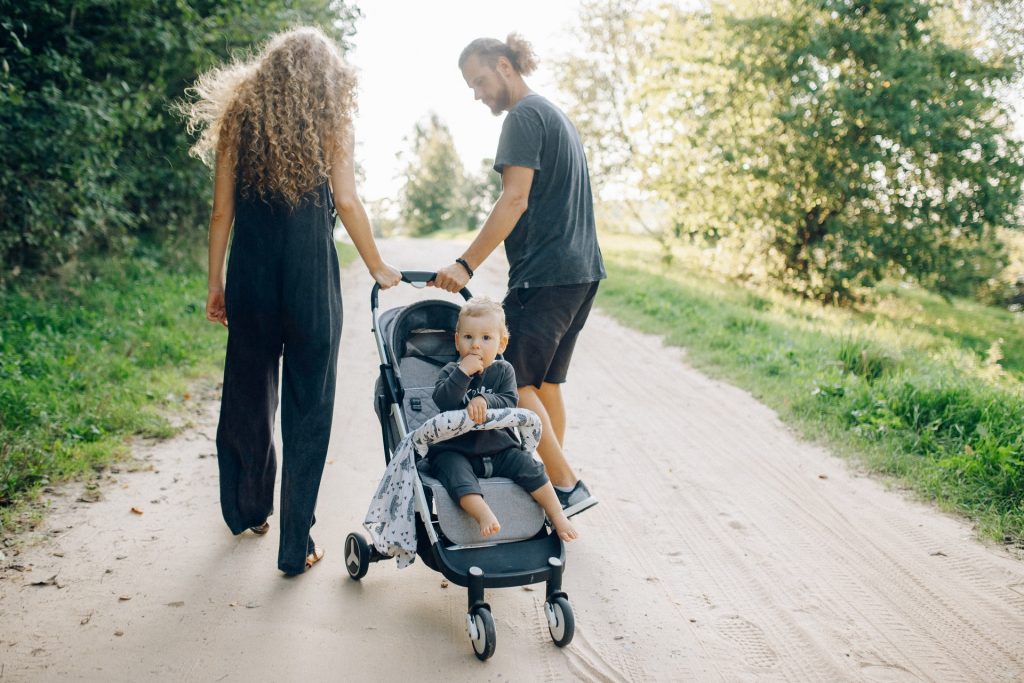 rodzice prowadzący wózek z dzieckiem ubranym w ciemne ciuchy dla niemowląt